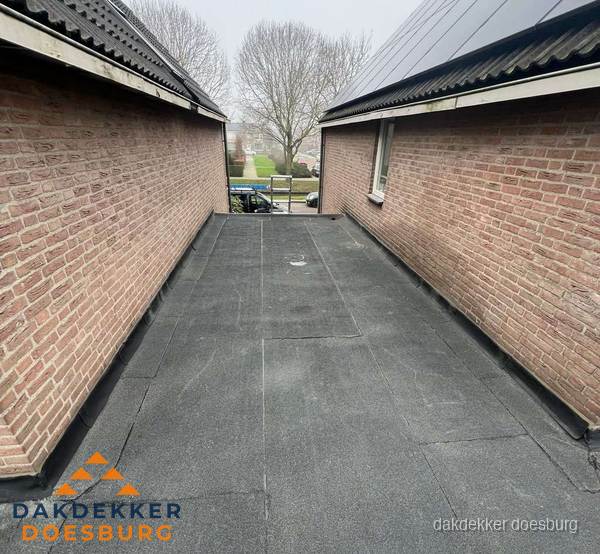 Plat dak met bitumen dakbedekking tussen bakstenen muren in Doesburg Plat dak met bitumen dakbedekking tussen bakstenen muren in Doesburg