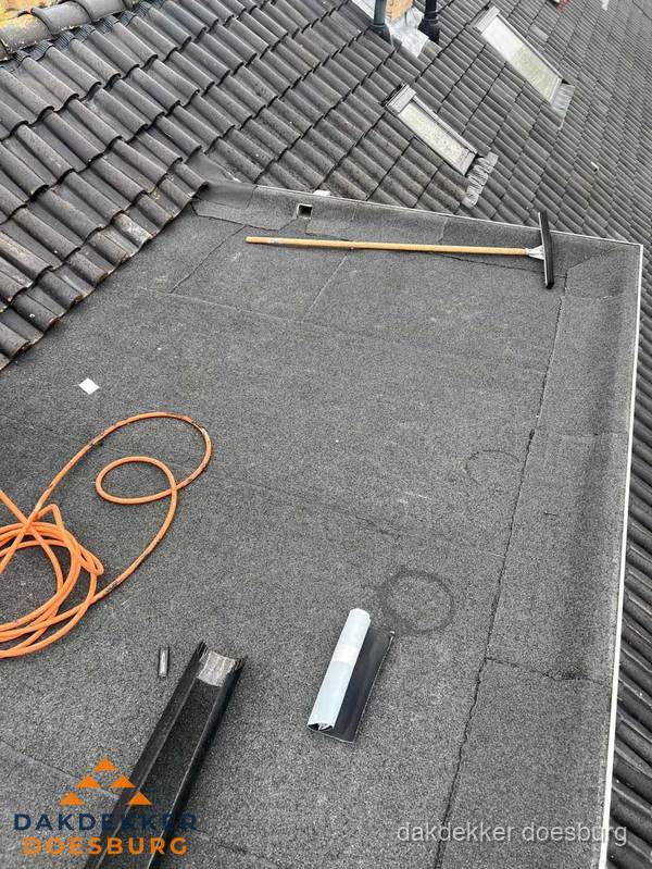 Plat dak reparatie met gereedschap en loodstroken in Doesburg
