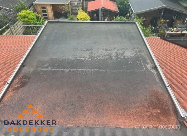 Verouderd plat dak met slijtage tussen schuine daken in Doesburg