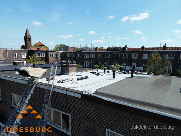 Dakdekkers aan het werk op plat dak in Doesburg