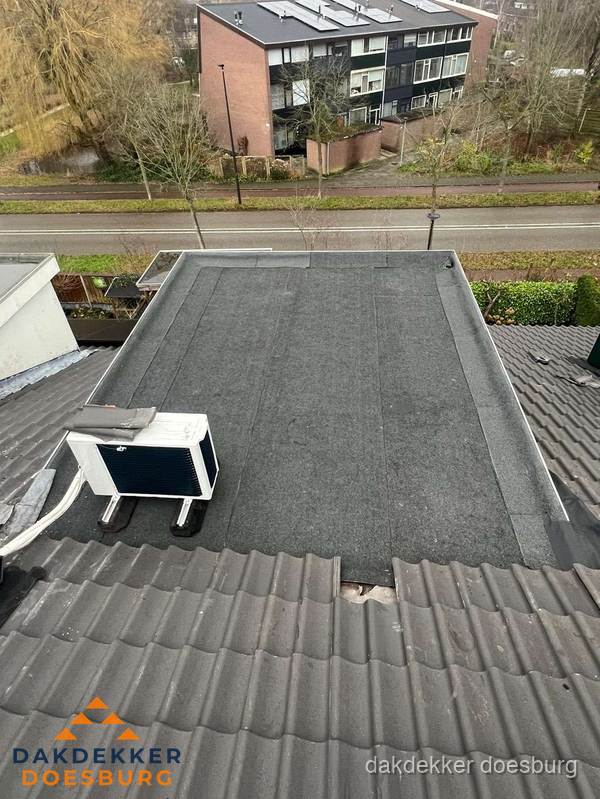 Plat dak inspectie met bitumen bedekking naast schuin pannendak in Doesburg